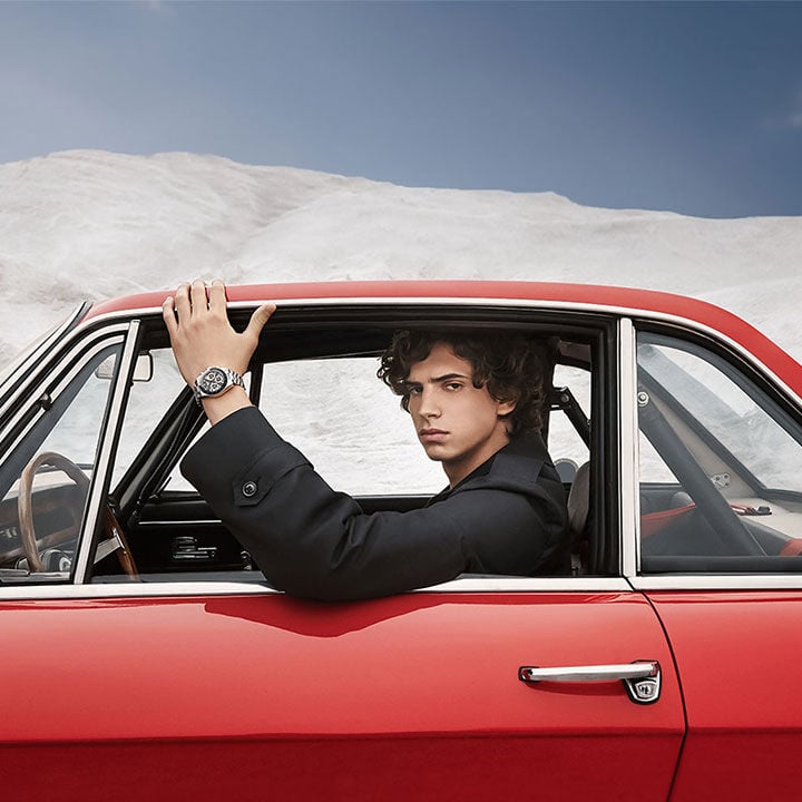Men driving a red car, wearing a PR516 watch