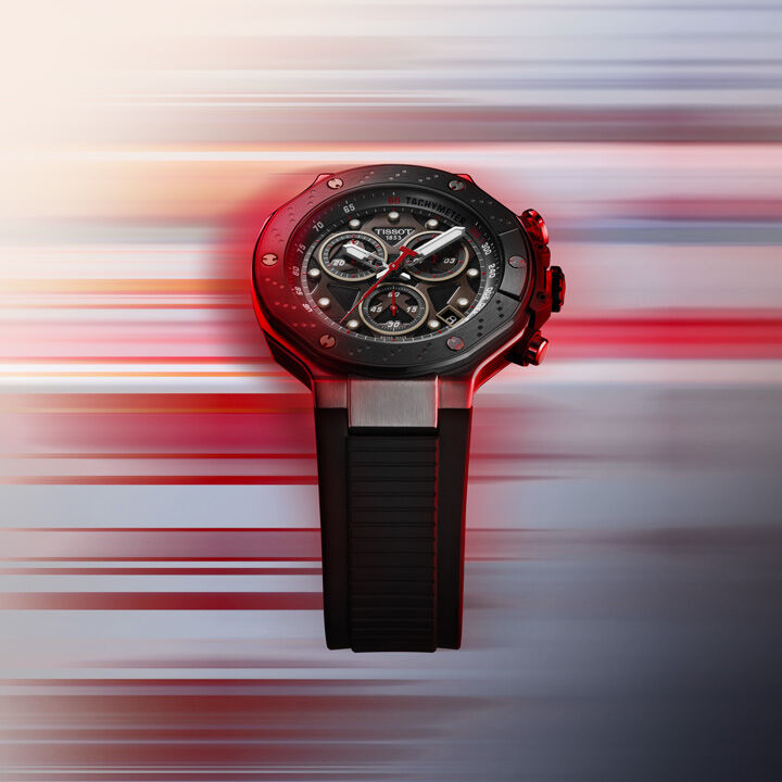 Tissot T-Race MotoGP 시계, 대담한 검은색 다이얼, 빨간색 액센트, 속도와 아드레날린을 불러일으키는 동적 모션 블러 배경.